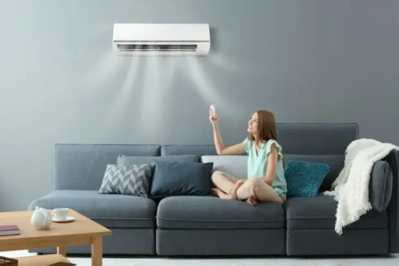 image showing a lady setting an air conditioner to cool