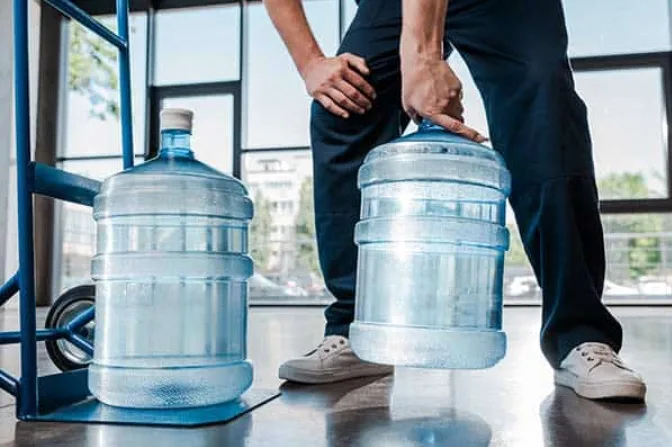 image showing someone lifting a water dispenser bottle from the neck