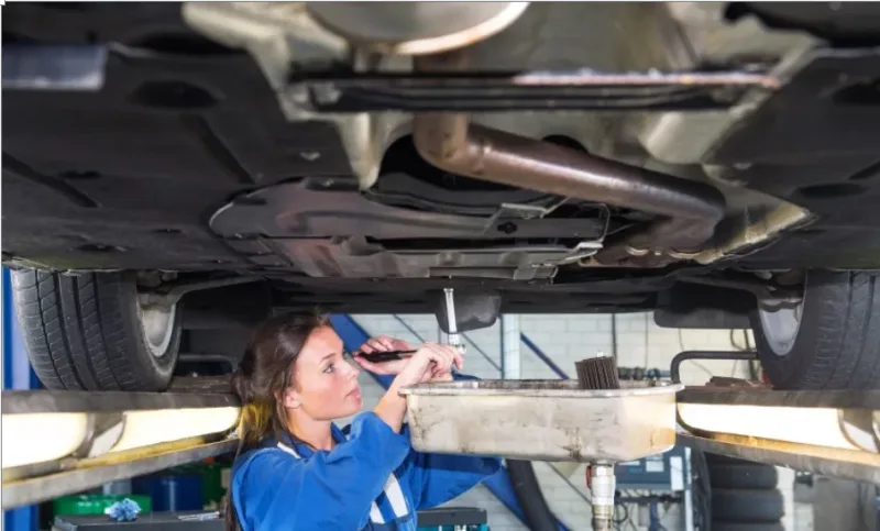 image showing an elevated vehicle and a technician draining its engine oil